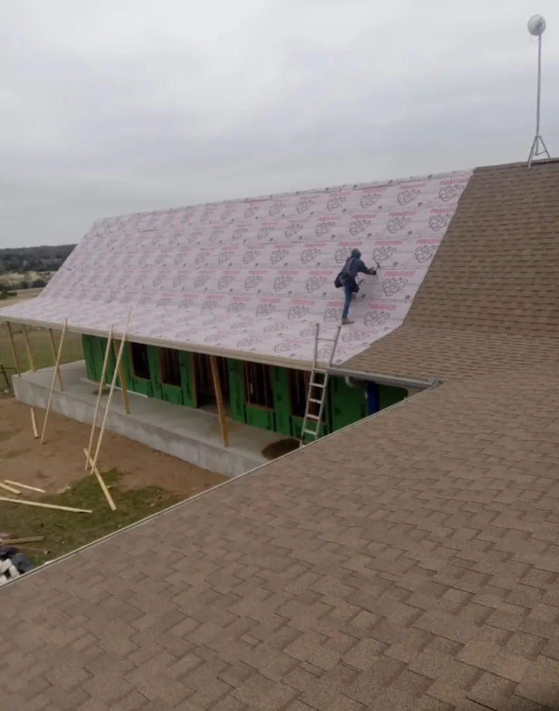 Worker preparing underlayment for a metal roof installation in Othello